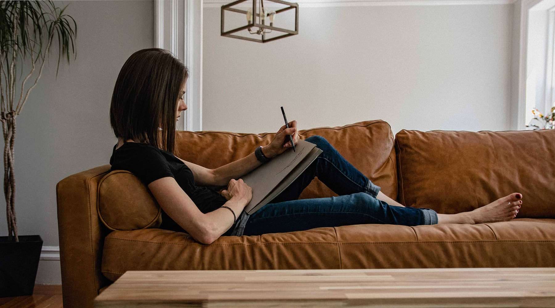 a woman sitting on a couch drawing